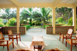 a porch with chairs and a table and a view of trees at G K Guest House in Kalkudah