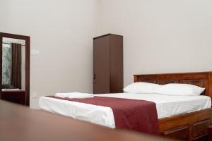 a bedroom with a bed with white sheets and a red blanket at G K Guest House in Kalkudah