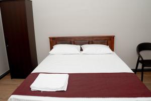 a bed with white sheets and white pillows at G K Guest House in Kalkudah