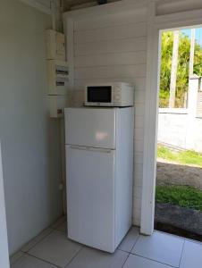 a kitchen with a microwave on top of a refrigerator at Chez Patrick in Sainte-Rose