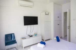 a white room with a tv and a blue chair at Nautica Luxe Beachfront in Oroklini