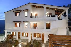a large white house with lights on at Goura Guesthouse Lake Doxa Mountain Retreats in Goura