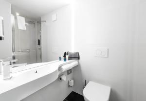 a white bathroom with a toilet and a sink at B&B HOTEL Nyon in Nyon