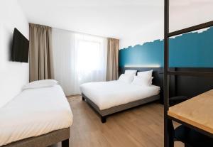 a hotel room with two beds and a table at B&B HOTEL Nyon in Nyon