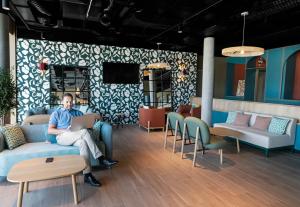 a man sitting on a couch in a room with a laptop at B&B HOTEL Nyon in Nyon