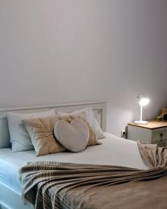 a white bed with a heart pillow on it at Apartment Caricia complex Carpe Diem Balchik - sea view & free parking in Balchik +42 photos