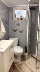 a bathroom with a toilet and a shower with butterflies on the wall at sunwave Tolo in Tolo
