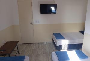 a room with two beds and a table and a tv at Hospedaria Barão in Campinas