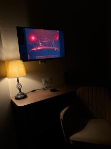 a desk with a lamp and a tv on a wall at Aarcos Stays in Greater Noida