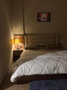 a bedroom with a large white bed and a lamp at Aarcos Stays in Greater Noida