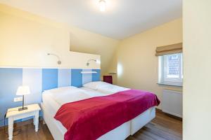 a bedroom with a large bed with a red blanket at Dat lütte Huus - Wohnung 1 in Husum