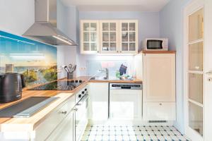 a kitchen with white cabinets and a sink at Dat lütte Huus - Wohnung 2 in Husum +10 photos