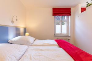a bedroom with a bed with a red blanket on it at Dat lütte Huus - Wohnung 2 in Husum