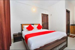 a bedroom with a large bed with red pillows at Royal Guest inn HSR Layout in Bangalore +4 photos