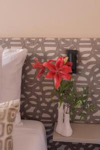 a red flower in a vase on a table next to a bed at Hotel Central Staytion in Amsterdam