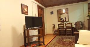 a living room with a flat screen tv on a stand at Goura Guesthouse Lake Doxa Mountain Retreats in Goura