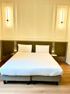 a large white bed in a room with two lights at Hotel Duca D'Aosta in Florence