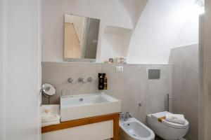 a bathroom with a sink and a toilet and a mirror at Dimora Sardaro Suites by BarbarHouse in Monopoli