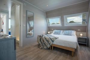 a bedroom with a bed and two windows on the wall at Bungalow Marina Azzurra in Lignano Sabbiadoro