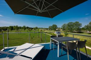 a patio with a table and chairs and an umbrella at Bungalow Marina Azzurra in Lignano Sabbiadoro