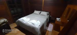 a bedroom with a bed with white sheets at Casa de Campo em Monte Verde in Camanducaia