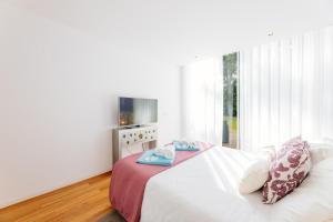 a white bedroom with a bed and a television at BestVillas Park Ofir in Esposende