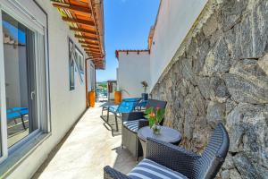 a patio with chairs and a table and a stone wall at Pousada Santorini in Búzios