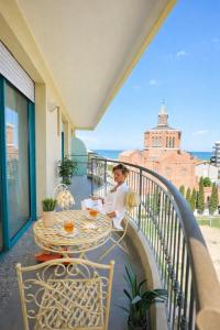 a woman sitting at a table on a balcony at Bellariva Feeling Hotel in Rimini