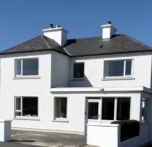 a white house with a black roof at The Townhouse Dungloe in Dungloe
