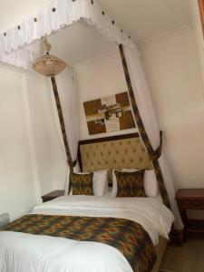 a bedroom with a canopy bed with white sheets and pillows at Kgcottage in Nairobi