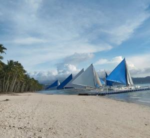 a group of blue and white sailboats on the beach at RenSea Haven Boracay in Boracay