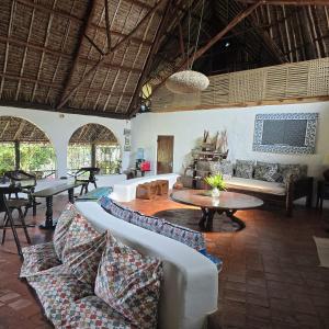 a living room with couches and a table and chairs at Sansuri Dreams Beach House in Msambweni