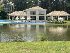 a large house with a swimming pool in front of a lake at Green Park Solanas Monoambiente Punta del Este in Punta del Este