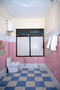 a pink bathroom with a toilet and a window at Panch Aarohan Hotel King in Pithorāgarh +39 photos