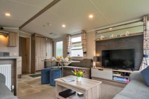 a living room with a large television and a couch at Finest Retreats - Pine Forest Lodge in Saint Enoder