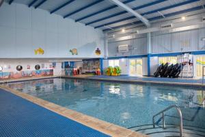 a large swimming pool in a large room at Finest Retreats - Pine Forest Lodge in Saint Enoder