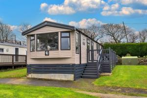 a tiny house sitting on the grass in a yard at Finest Retreats - Pine Forest Lodge in Saint Enoder