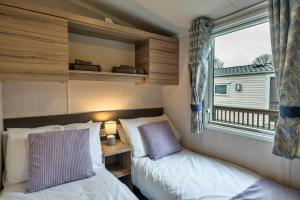 two beds in a small room with a window at Finest Retreats - Pine Forest Lodge in Saint Enoder +19 photos