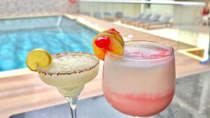 two cocktails sitting on a table next to a pool at Hotel Chayrama in Santa Marta