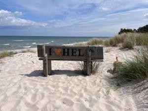 a wooden bench in the sand on a beach at Przystanek Hel in Hel