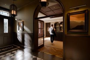 a man walking down a hallway with a mirror at The Kithmore in St. Andrews
