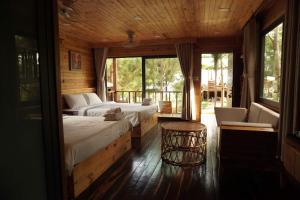 a bedroom with two beds and a chair and windows at The Lake Hill Farm Tà Đùng in Biđong +57 photos