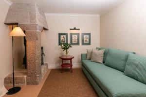 a living room with a green couch and a table at Valverde Santar Hotel & SPA - Relais & Châteaux in Santar +110 photos