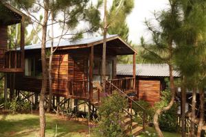 a log cabin with a porch and trees at The Lake Hill Farm Tà Đùng in Biđong