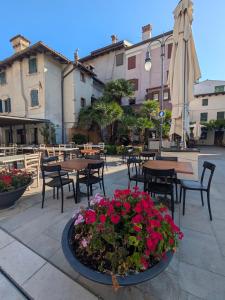 a patio with tables and chairs and flowers and an umbrella at Casa Vianella in Grado
