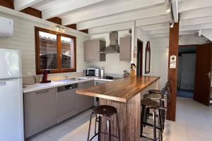 a kitchen with a counter and stools in it at chalet with swimming pool in leisure park in Gujan-Mestras