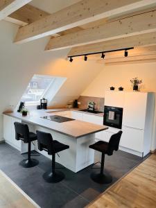 a kitchen with a large white island with black chairs at Ferienwohnung Kastanieneck in Kevelaer