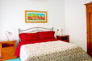 a bedroom with a bed with red pillows and a painting on the wall at Donna Alda Affittacamere Capitello dal 2012 in Villammare