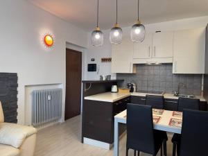 a kitchen with white cabinets and a table and chairs at Nido Alpino - casetta con giardino, vista montagne in Tirano