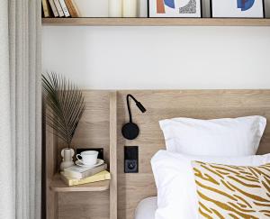 ein Schlafzimmer mit einem Bett mit hölzernem Kopfteil in der Unterkunft Le Riviera Collection, Signature Collection by Best Western in Nizza